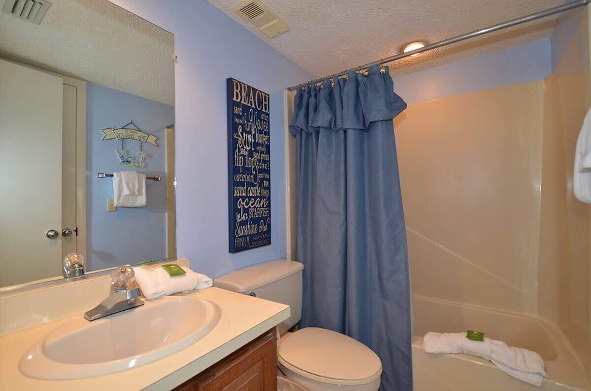 A bathroom with a sink, toilet, and shower curtain.