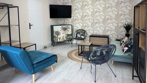 Un saló modern amb televisió de pantalla plana, un sofà blau, un armari de fusta i un paper pintat amb motius.