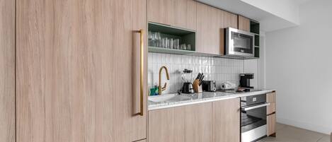 A modern kitchen with wooden cabinets, a microwave, a sink, and a dishwasher.