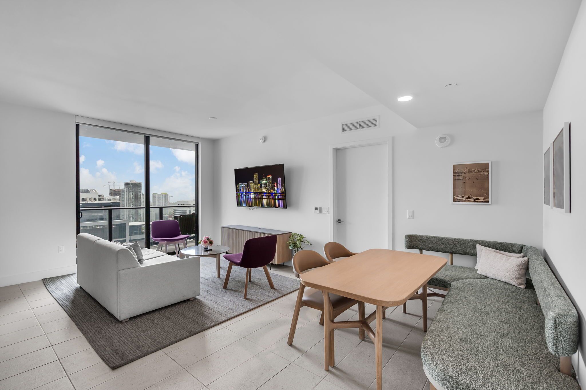 A modern living room with a sofa, dining table, chairs, and a TV.