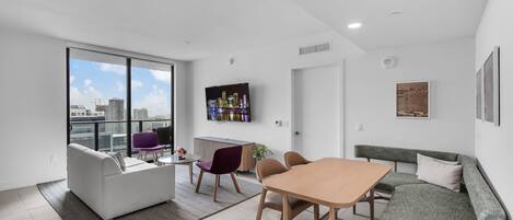 Una sala de estar moderna con sofá, mesa de comedor, sillas y televisor.