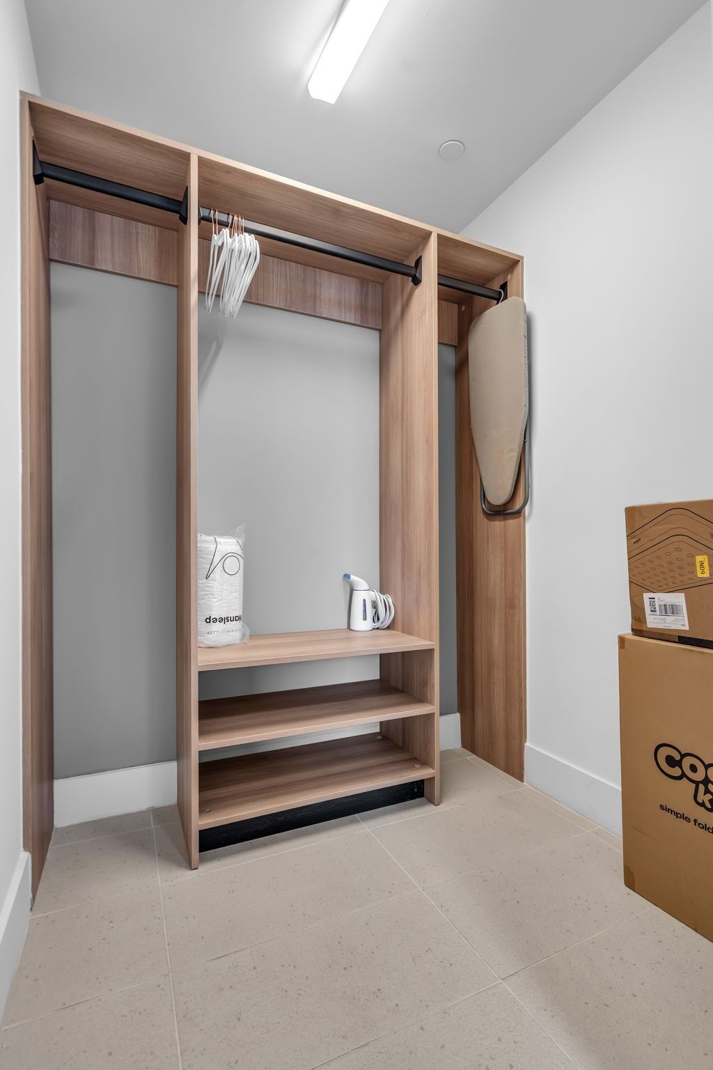 Un vestidor con estantes de madera, una barra para colgar ropa y un baúl para guardar objetos.