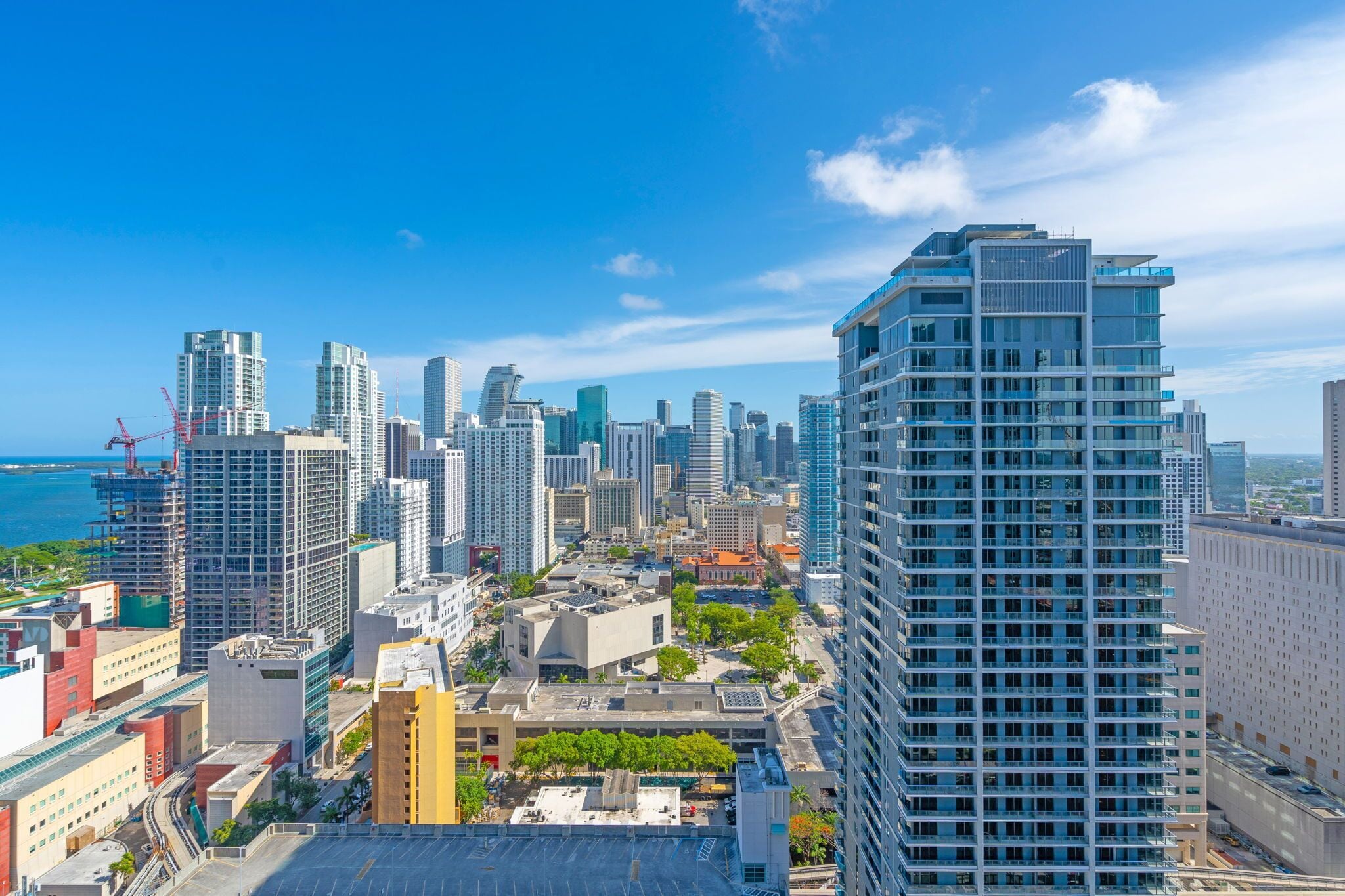 A cityscape with high-rise buildings, a clear sky, and a body of water in the distance.