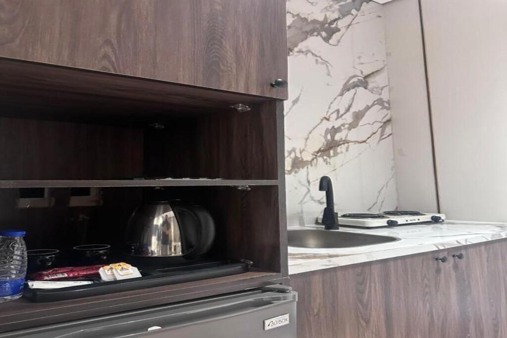 Una cucina con fornello, bollitore e una bottiglia d'acqua sul bancone.