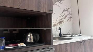 Una cucina con fornello, bollitore e una bottiglia d'acqua sul bancone.
