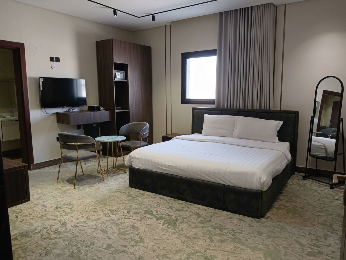 Une chambre d’hôtel comprenant un lit, une télévision, un bureau avec une chaise et une fenêtre avec des rideaux.