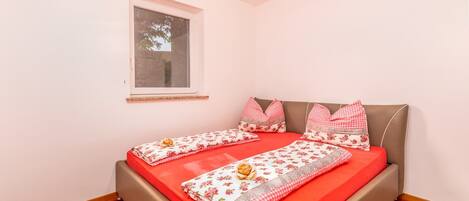 Un dormitorio con cama, ventana y suelo de madera.