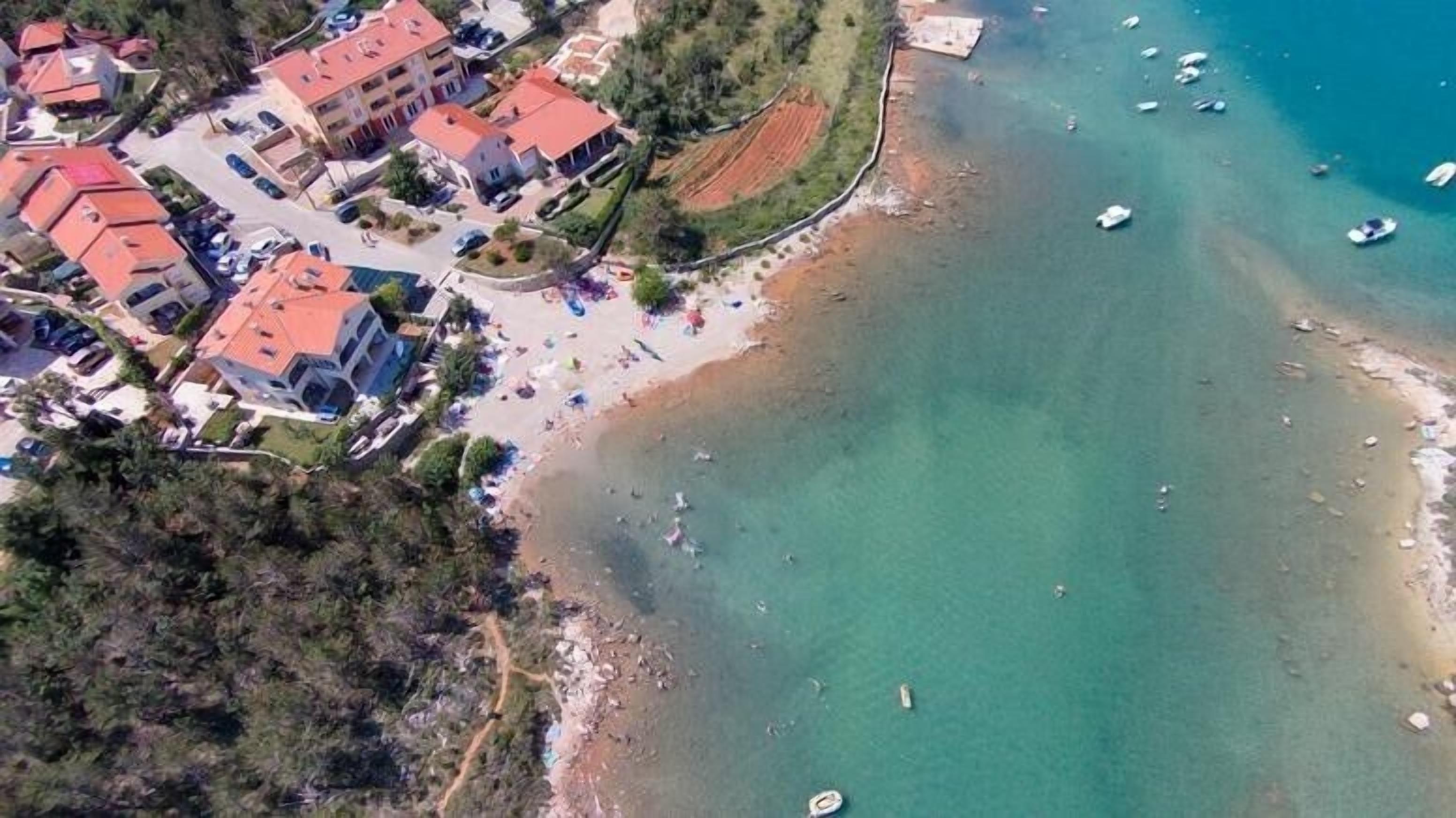 Vista aérea de una zona costera con edificios, una playa y barcos.