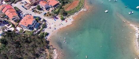 Vista aérea de una zona costera con edificios, una playa y barcos.