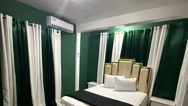 Ein Hotelzimmer mit Bett, Vorhängen, einer Klimaanlage und einem Nachttisch.