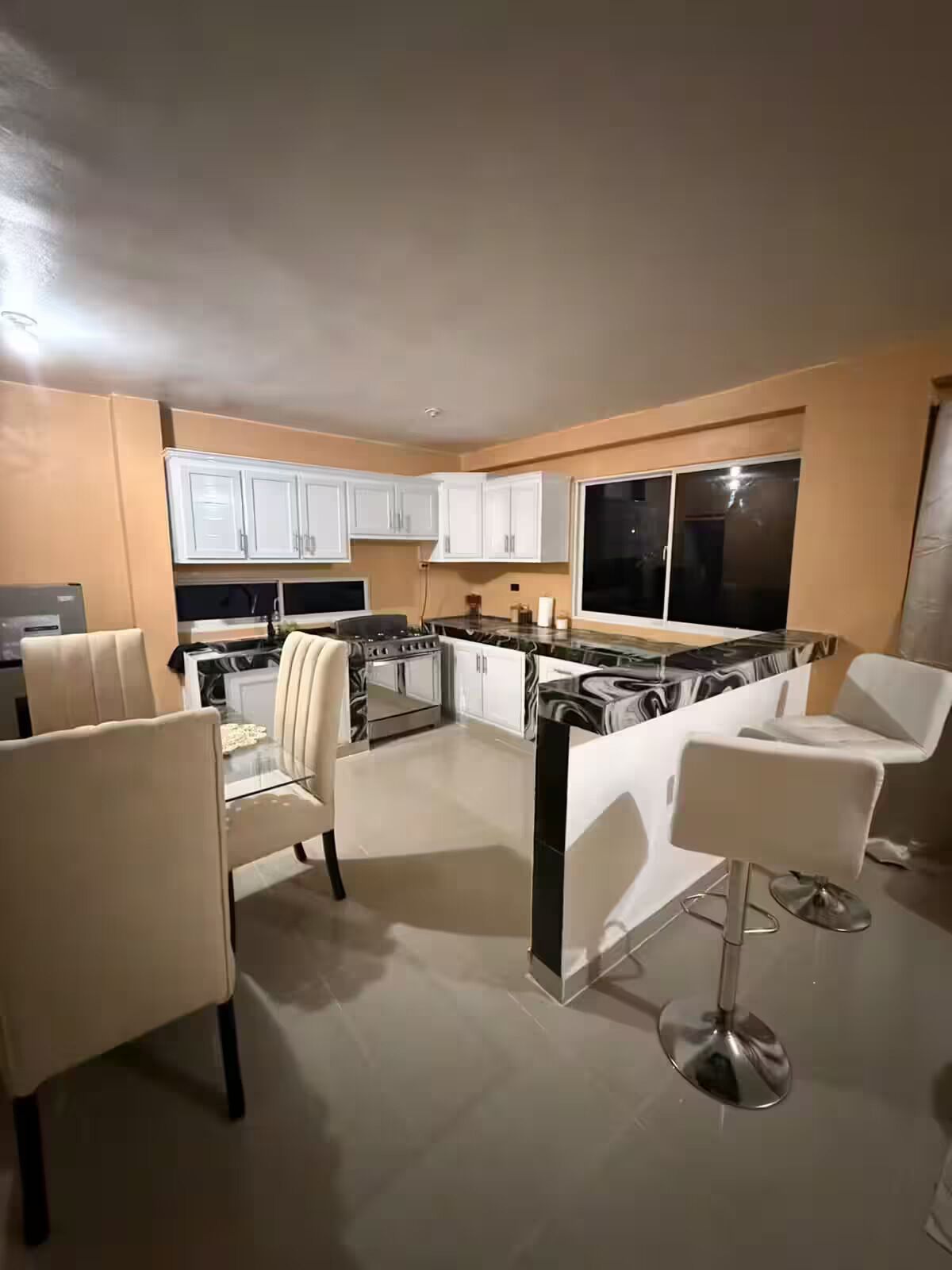 A modern kitchen with white cabinets, a central island, and bar stools.