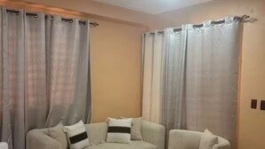 Ein Wohnzimmer mit einer Couch, zwei Hocker und einem Teppich mit Fischgrätmuster.