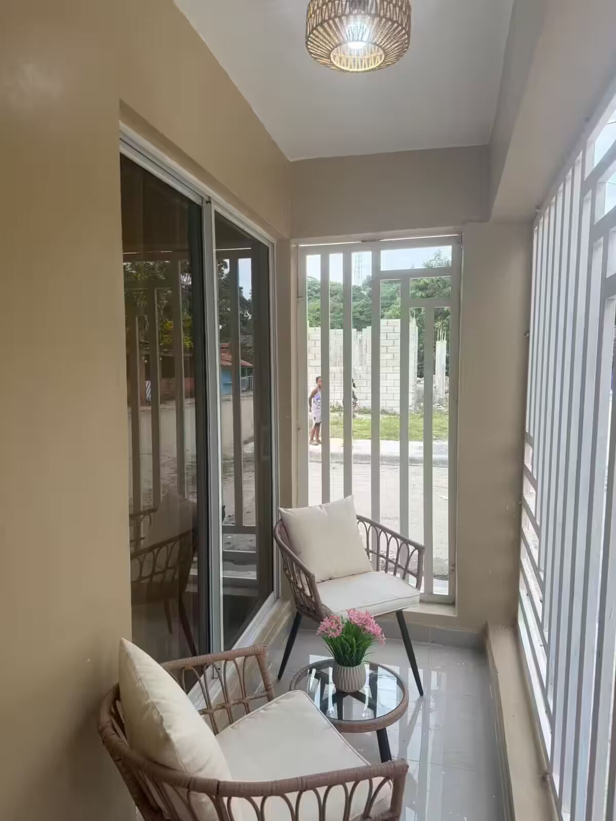 A balcony with wicker chairs, a glass table, and a potted plant.