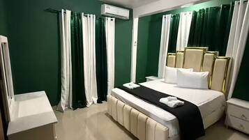 A hotel room with a bed, bedside table, and an air conditioning unit.