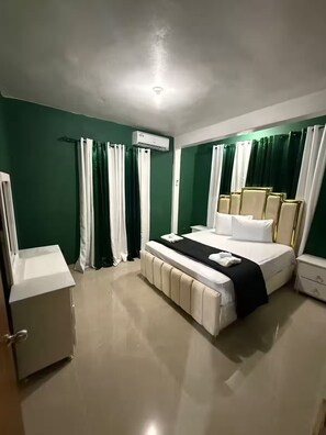 Una habitación de hotel con cama, mesita de noche y equipo de aire acondicionado.