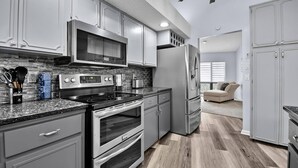 A modern kitchen with stainless steel appliances, a microwave, oven, and a refrigerator. - Footprints In The Sand | 3BR Private Pool Home | Near Palm Coast and Flagler Beaches (Palm Coast)