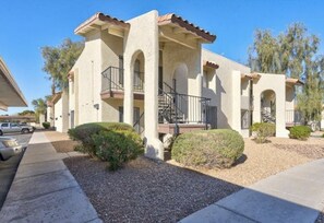A two-story building with a balcony, a covered entryway, and a small garden area. - Jamming Jericho 2 bedrooms (Las Vegas)