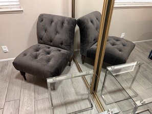A room with a grey tufted sofa, a glass display stand, and a wooden floor. - Jamming Jericho 2 bedrooms (Las Vegas)