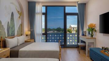 A hotel room with two beds, a desk, a TV, and a balcony with a view.