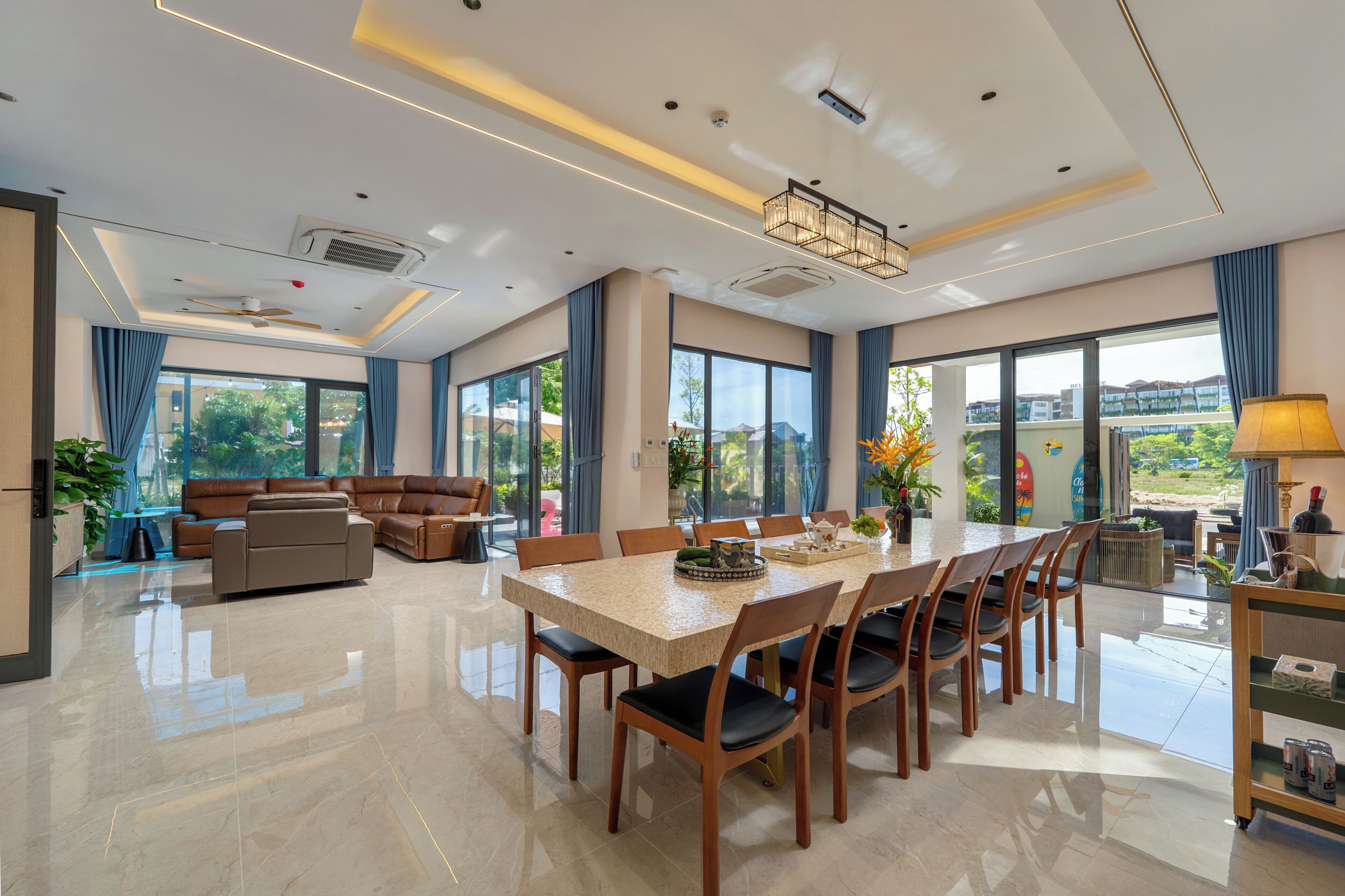 Amplia sala de estar con una gran mesa de comedor, asientos cómodos y vistas a través de amplias ventanas.