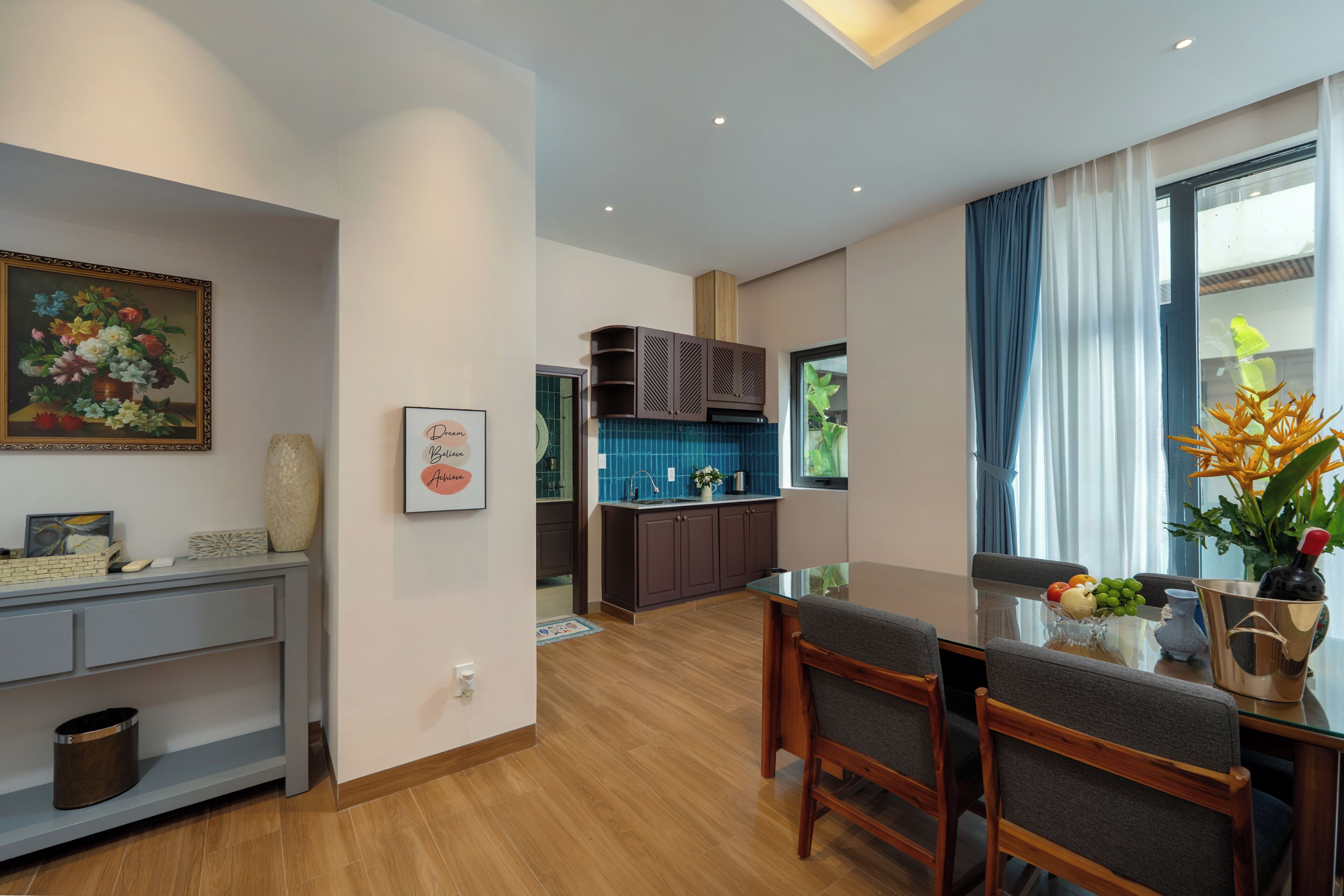Una cocina moderna con salpicadero azul, armarios de madera y un comedor con mesa y sillas.