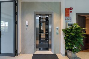 An elevator with a modern design, a potted plant, and a wall-mounted phone. - Bao Anh Villa (Da Nang)