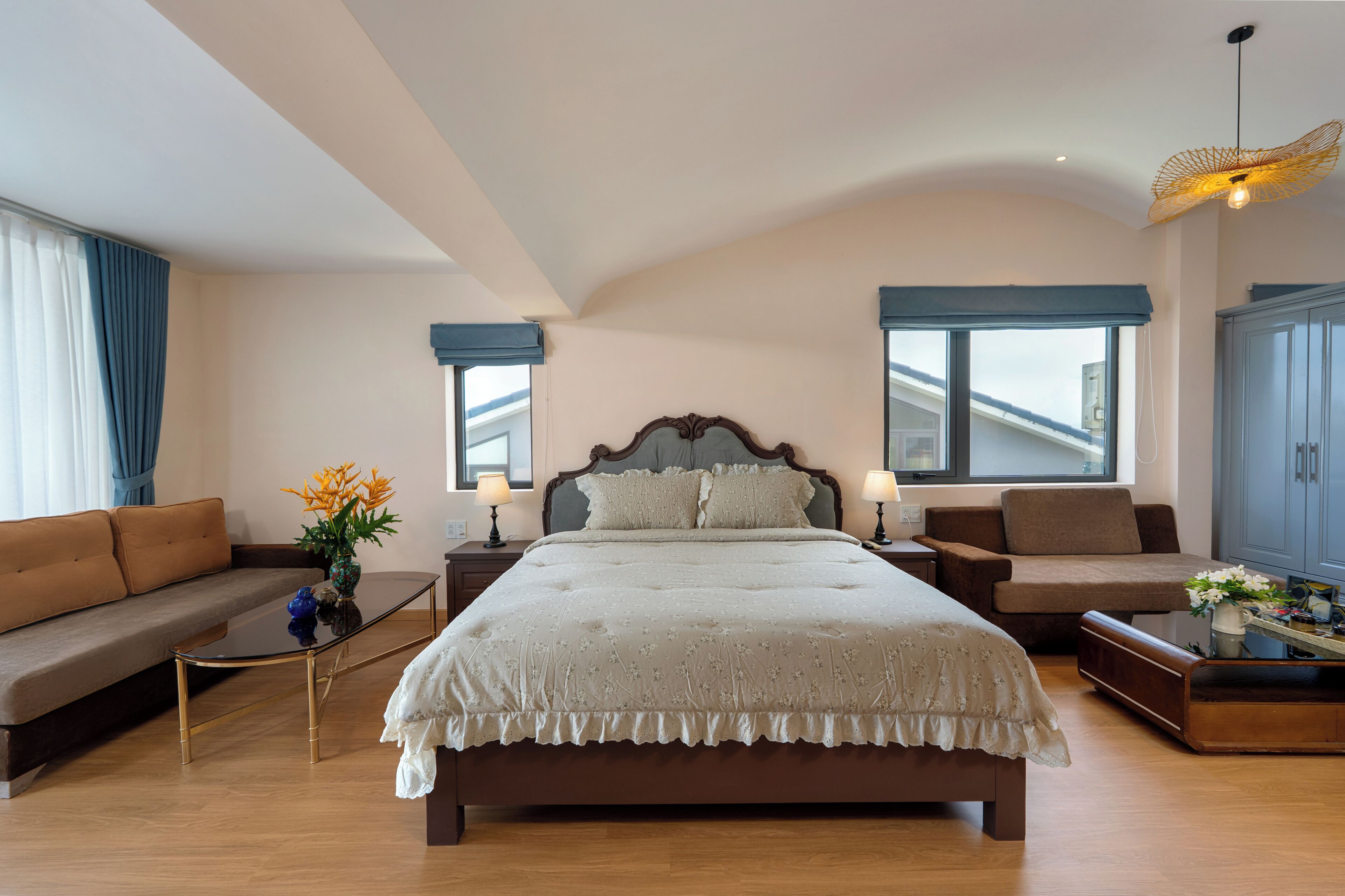 A bedroom with a large bed, a sofa, a coffee table, and a desk with a lamp.