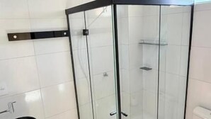Un baño moderno con ducha de vidrio, inodoro y lavamanos.