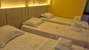 Habitación de hotel con dos camas, cada una con almohada y una toalla doblada que muestra el logotipo del hotel.