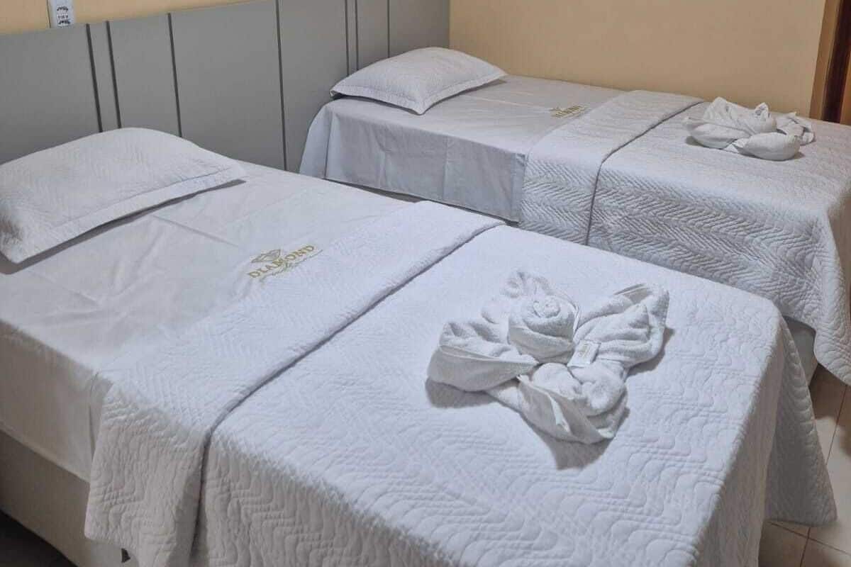 Una habitación de hotel con dos camas individuales, cada una con almohada y manta.