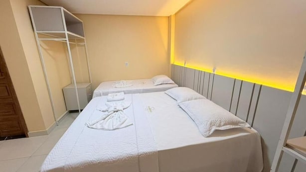 Una habitación de hotel con dos camas, un armario y una mesita de noche.