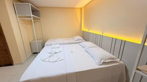 Een hotelkamer met twee bedden, een kledingkast en een nachtkastje.