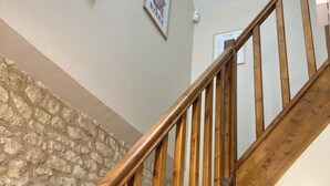 A wooden staircase with a stone wall on one side and a ceiling light.