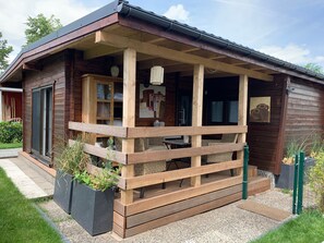 A wooden cabin with a porch, a door, and a window.