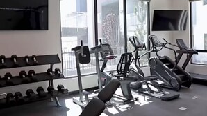 Une salle de sport équipée de machines d’exercice, d’haltères et dotée de grandes fenêtres.