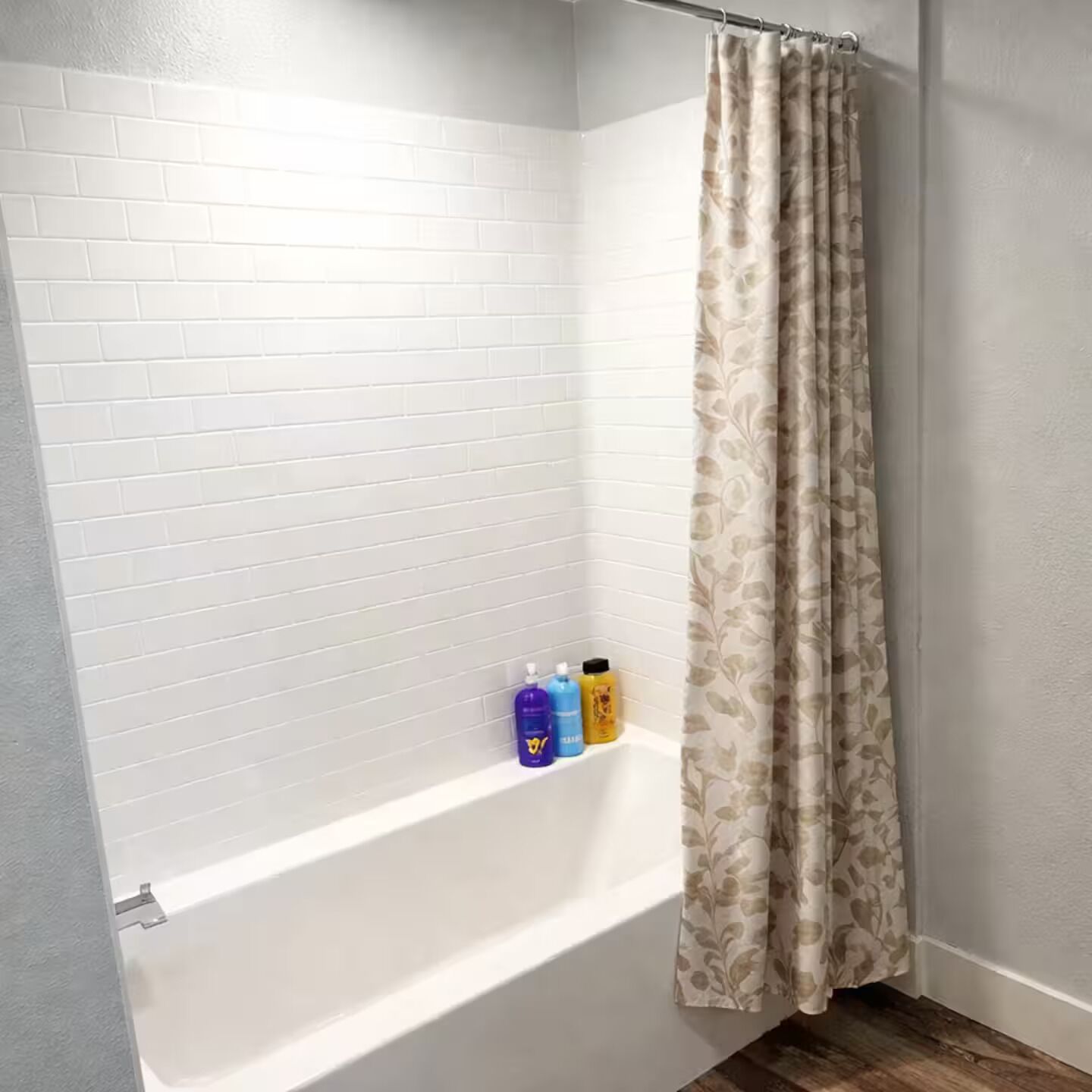 Ein Badezimmer mit weiß gefliesten Wänden, einer Badewanne und einer Duschvorhang.