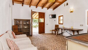 Una stanza con un divano bianco, un armadio in legno, una televisione e un pavimento in pietra.