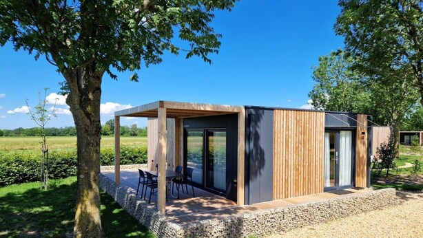 A modern outdoor structure with a covered seating area, a stone base, and a large tree in the foreground. - Holiday Home With 1 Bedroom (Berg en Terblijt)