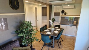 A modern living space with a dining area, kitchen, and a large potted plant. - Holiday Home With 1 Bedroom (Berg en Terblijt)