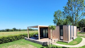 A modern outdoor structure with a covered seating area, a small garden, and a view of the surrounding landscape. - Holiday Home With 1 Bedroom (Berg en Terblijt)