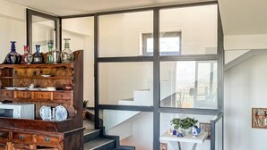 Un interior modern amb una escala, una zona de menjador i vista cap a l'exterior.