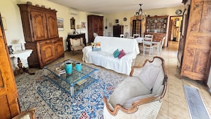A spacious living room with a white sofa, wooden furniture, a glass coffee table, and a patterned rug. - La Musardière - Air Conditioning, Pool with a View - Sleeps 8 (Villeneuve-lès-Avignon)