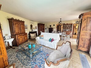 A spacious living room with a white sofa, wooden furniture, a glass coffee table, and a patterned rug. - La Musardière - Air Conditioning, Pool with a View - Sleeps 8 (Villeneuve-lès-Avignon)