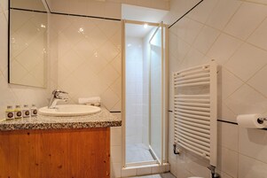 Une salle de bain équipée d’un lavabo, d’un miroir, d’une douche et d’un porte-serviettes.