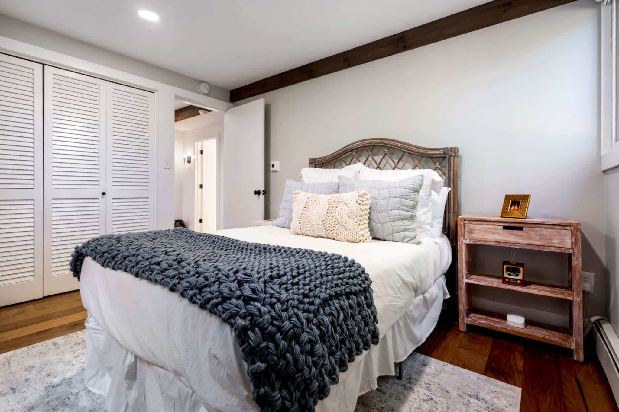 A bedroom with a bed, a bedside table, a wardrobe, and a door.