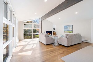 Una sala de estar moderna con chimenea, ventanas amplias y vistas al exterior.