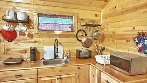 L’intérieur d’un chalet en bois comprend un coin cuisine équipé d’un évier, d’une cuisinière et d’un four à micro-ondes.