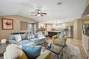 Ein modernes Wohnzimmer mit einer Couch, Sesseln, einem Couchtisch und einem Deckenventilator.