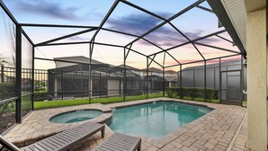 A covered outdoor swimming pool with lounge chairs and a view of residential buildings. - 6BR house sleeps 16 with private pool (Kissimmee)