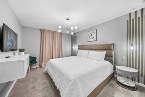 A modern bedroom with a bed, bedside table, and a television. - 6BR house with pool near Disney area (Kissimmee)